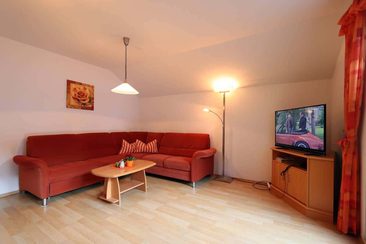 Wohnzimmer mit großer roter Couchecke und Flachbild-SAT-TV